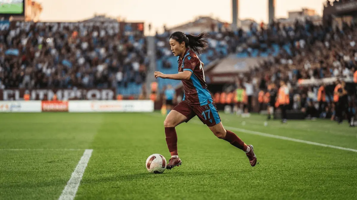 South Korean midfielder in Trabzonspor kit controlling ball in women's football match action