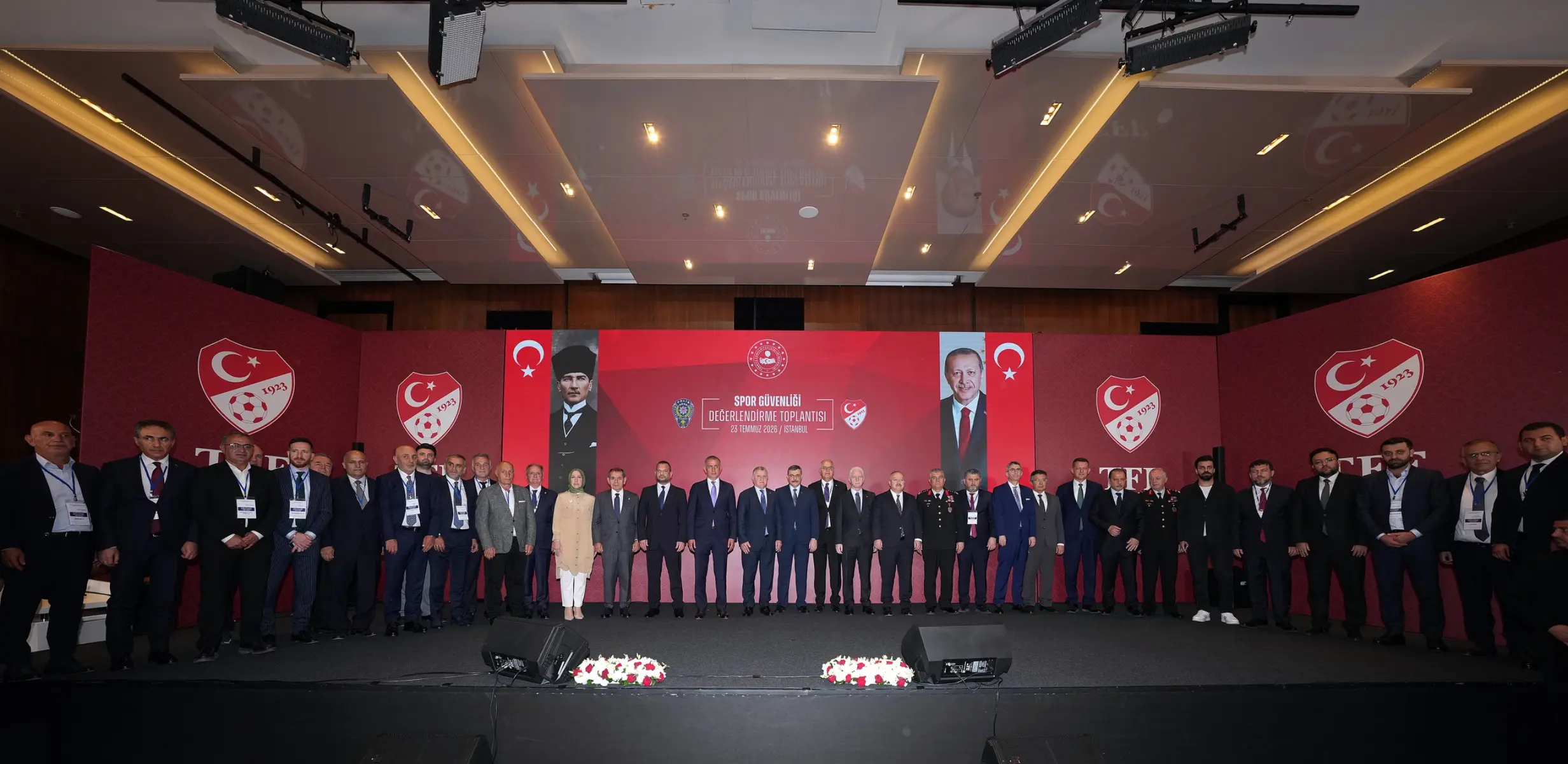 Group photo of officials at the TFF Spor Güvenliği Değerlendirme Toplantısı with Turkish flags and banners.