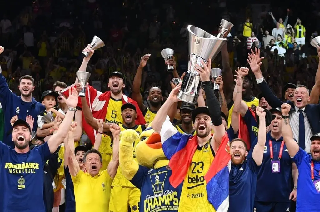 Fenerbahce Beko basketball players celebrating with a championship trophy and jerseys