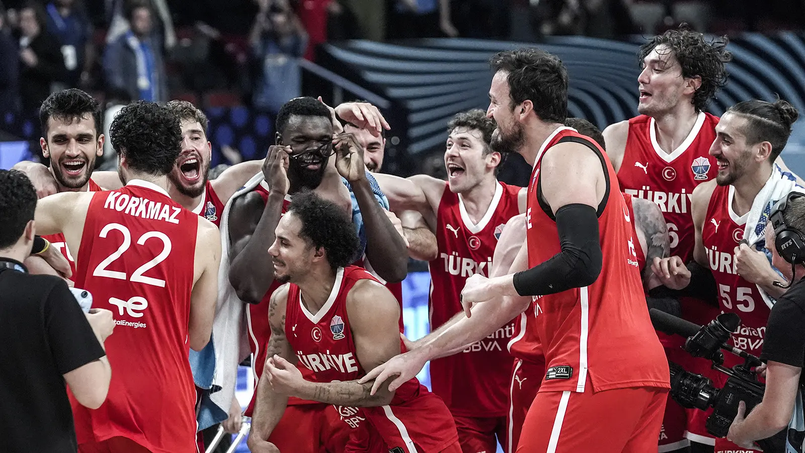 Turkish national basketball team players in red jerseys celebrating a victory on the court