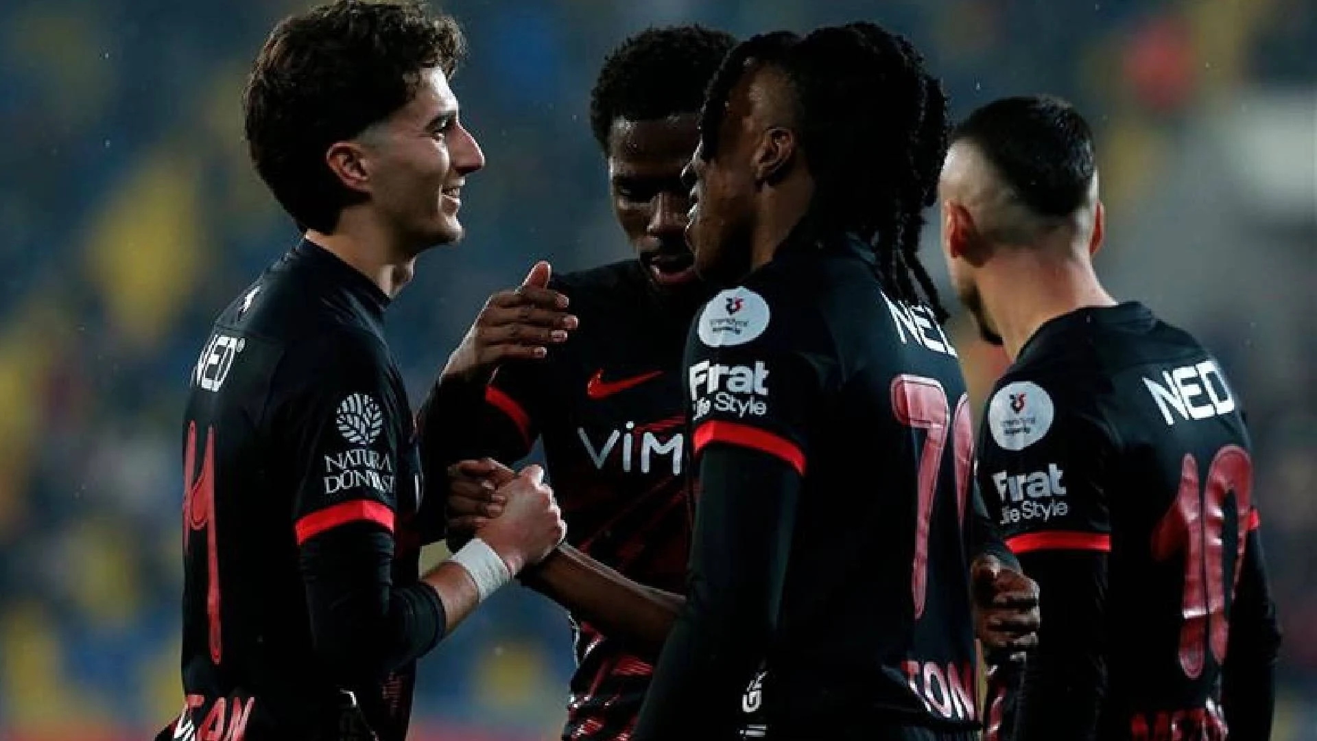 Siyah formalarıyla sahada birbirini tebrik eden futbolcular