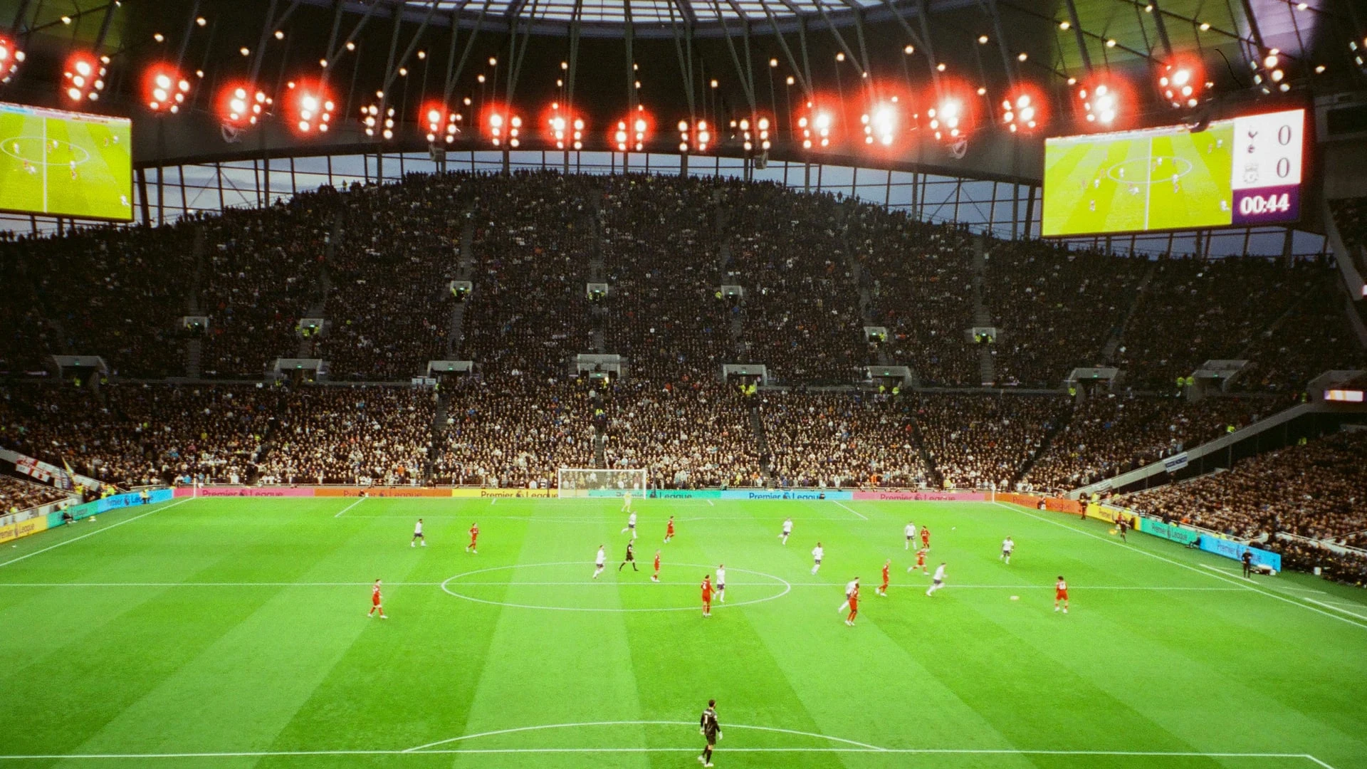İnsanlarla dolu bir futbol stadyumunda devam eden bir maç.