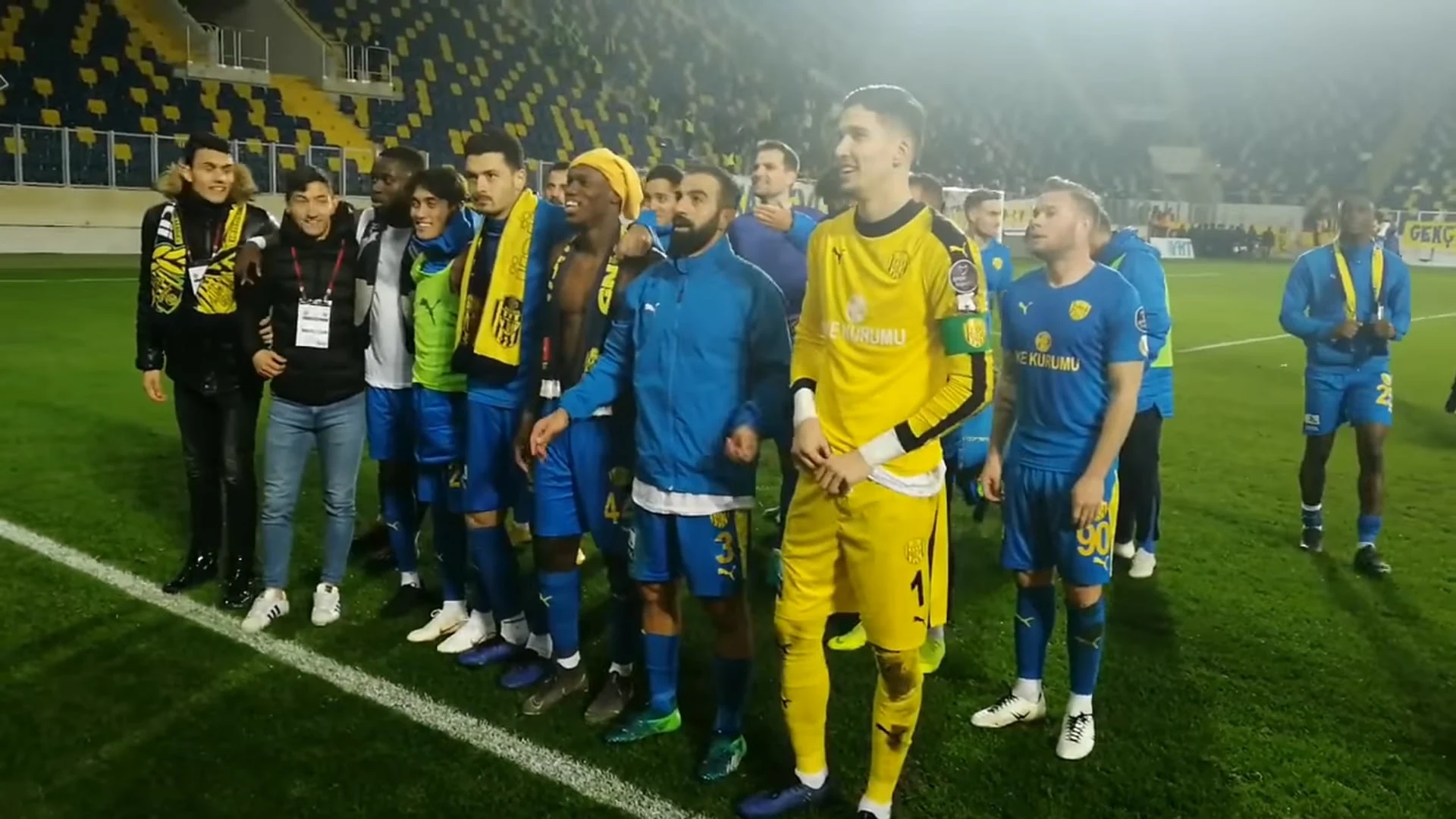 MKE Ankaragücü oyuncuları sahada yan yana dizilmiş şekilde poz veriyor.