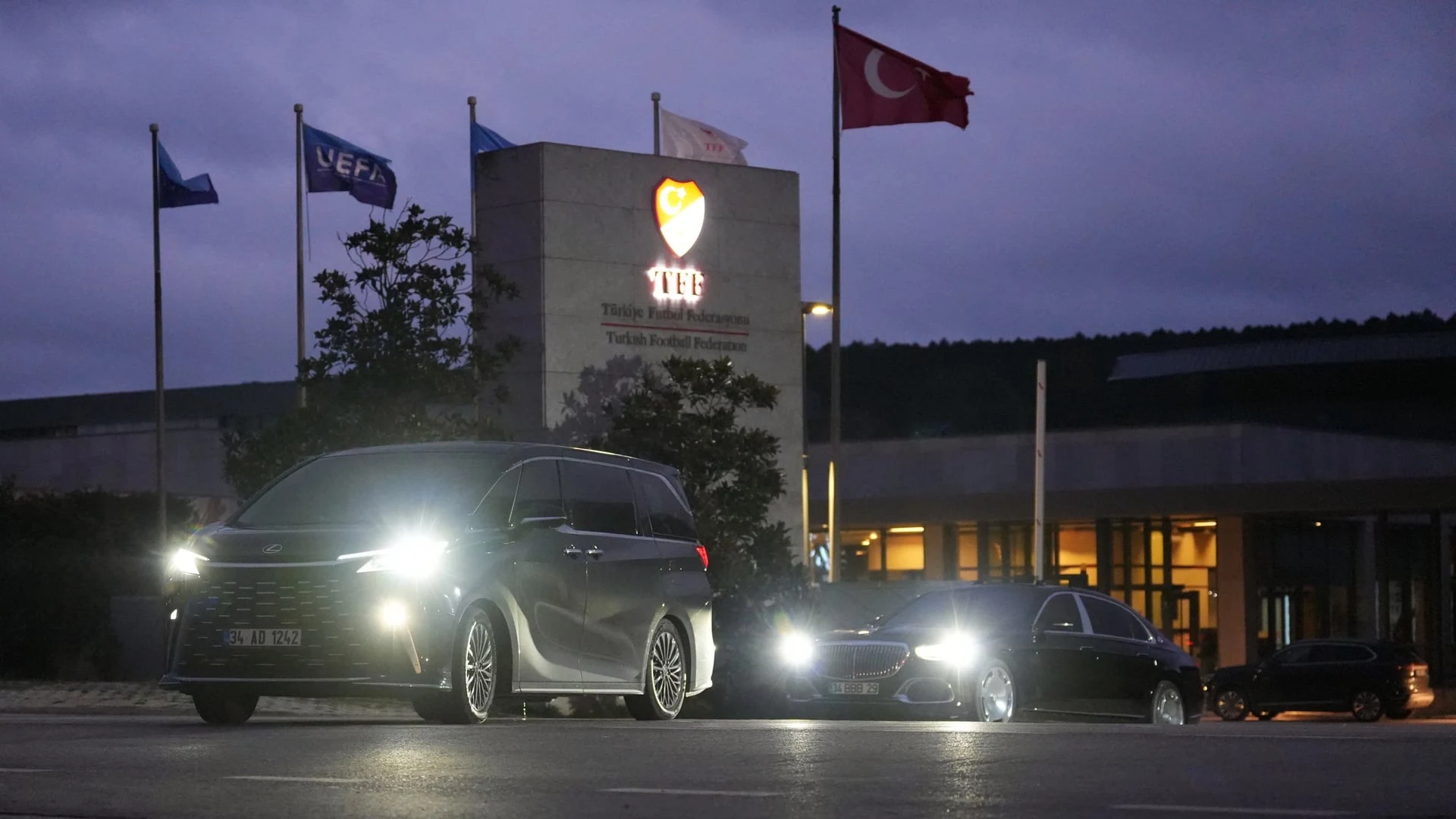 Türkiye Futbol Federasyonu binası önünde park etmiş lüks araçlar ve dalgalanan bayraklar.